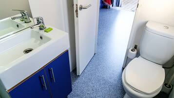 A bathroom with a white sink, blue cabinets, and a white toilet.
