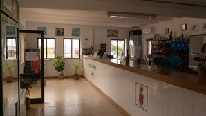Un espace d’accueil avec un comptoir, des plantes en pot et une vue sur l’extérieur.