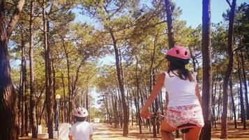 Un sendero arbolado con dos personas montando en bicicleta, una con casco y la otra sin él.
