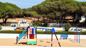 Une aire de jeux avec des balançoires et un toboggan, un banc et une table de pique-nique.