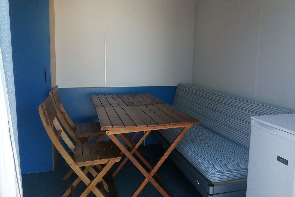 Een kleine kamer met een houten tafel, een bank en een bed.