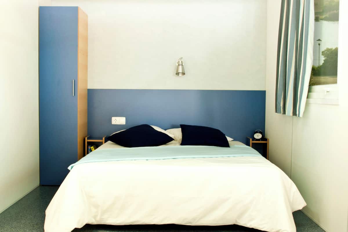 Un dormitorio con cama, mesita de noche, lámpara de pared y armario.