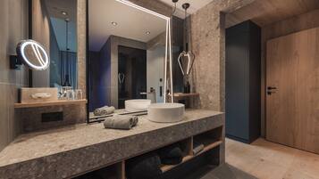 A modern bathroom with a large mirror, a round light, a white sink, and a wooden door.