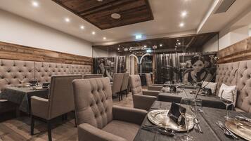 A restaurant with wooden ceiling beams, tufted booths, and a modern interior design.