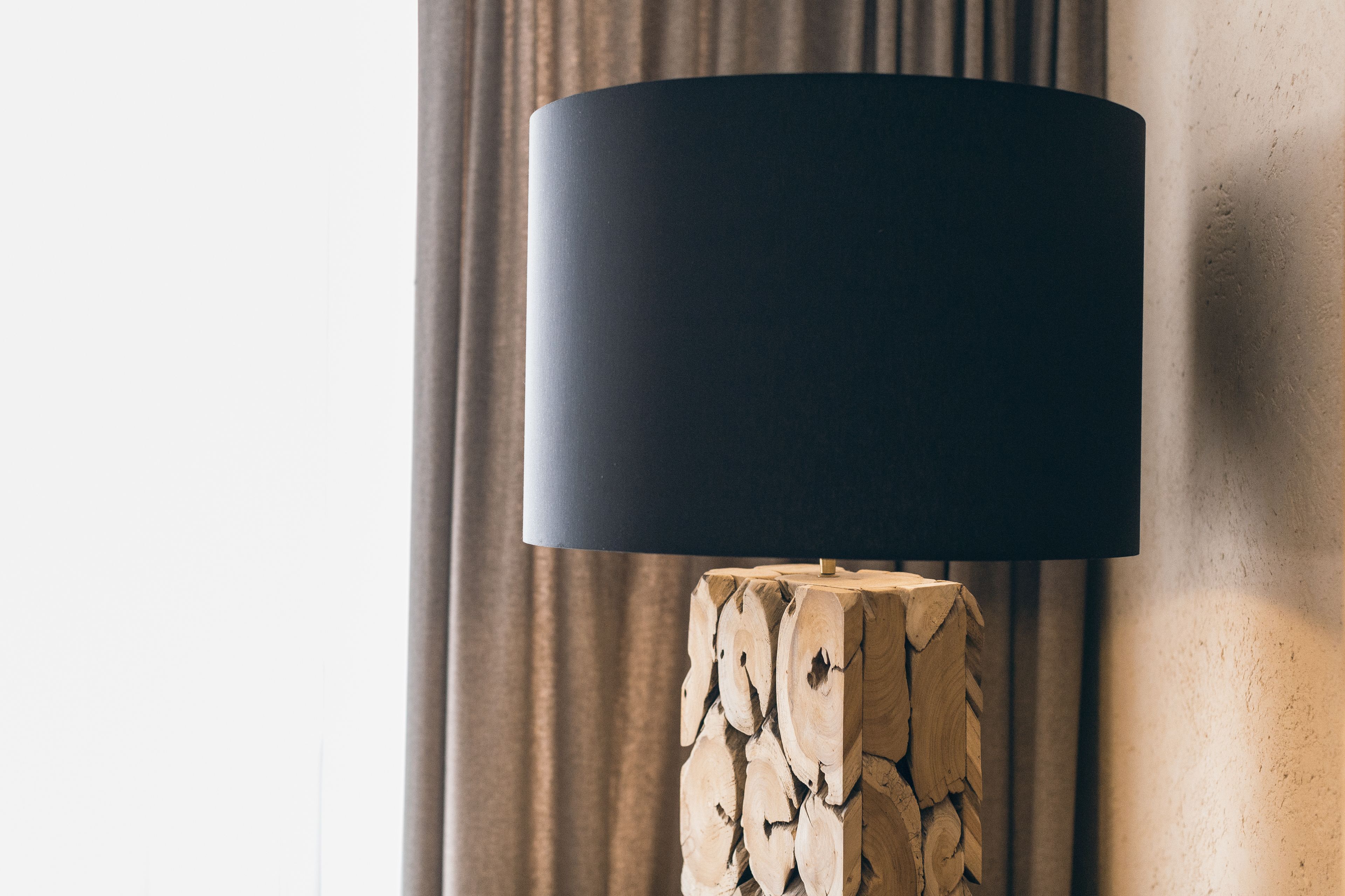 Eine moderne Lampe mit schwarz lackiertem Schirm auf Holzfuß.
