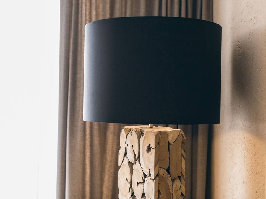 Eine moderne Lampe mit schwarz lackiertem Schirm auf Holzfuß.