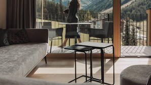 A modern living room with a large sliding glass door leading to a balcony with a mountain view. - Alpine Resort Sportalm (Sankt Leonhard im Pitztal)