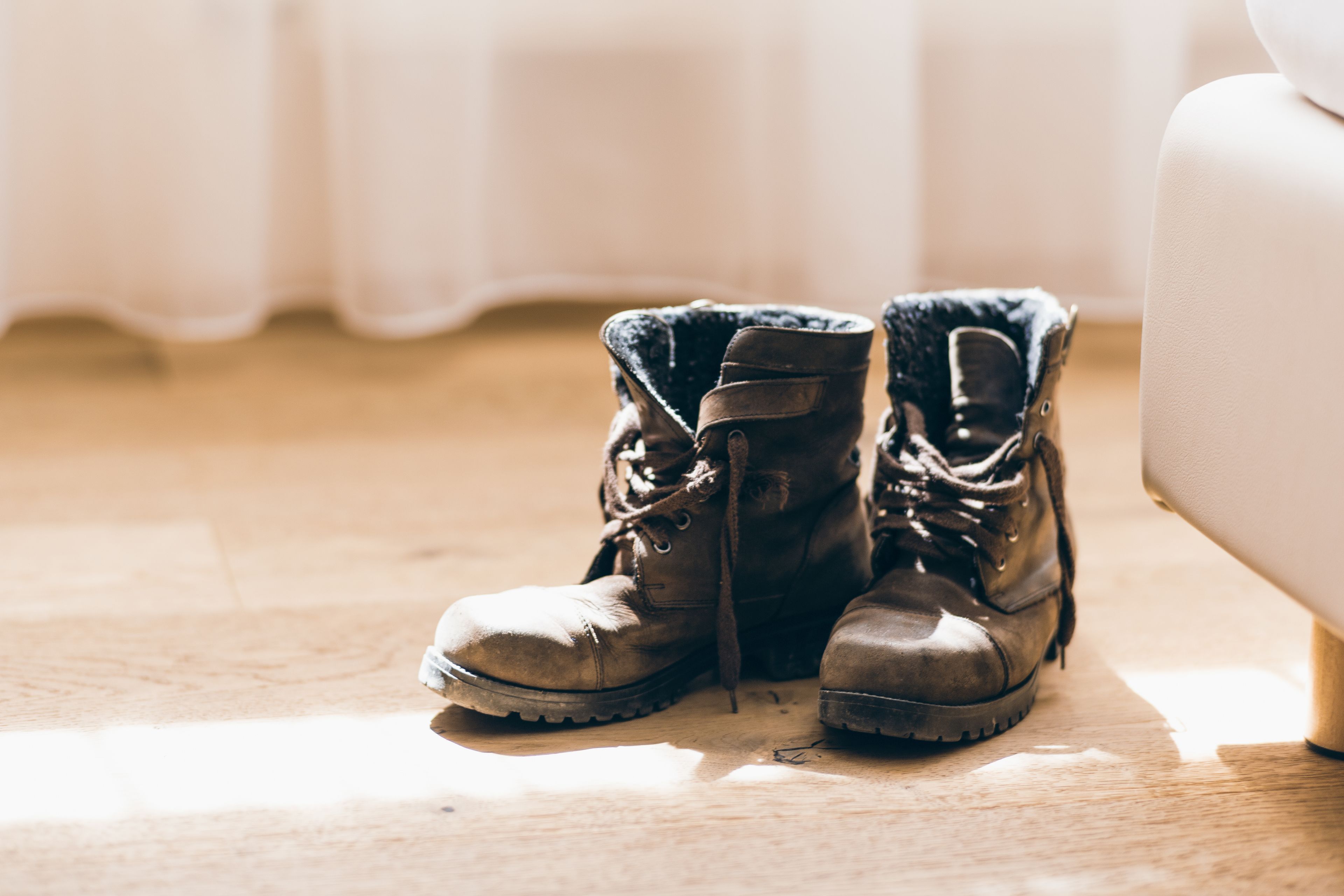 Un par de botas sobre un suelo de madera, junto a una silla blanca.