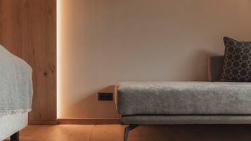 A minimalist room with a grey sofa, a patterned pillow, and a wooden wardrobe.