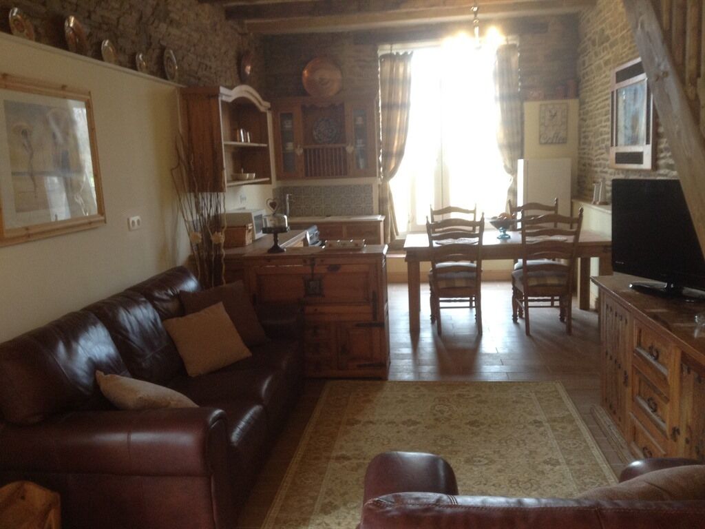 A cozy living room with a leather sofa, wooden dining table, and a television.