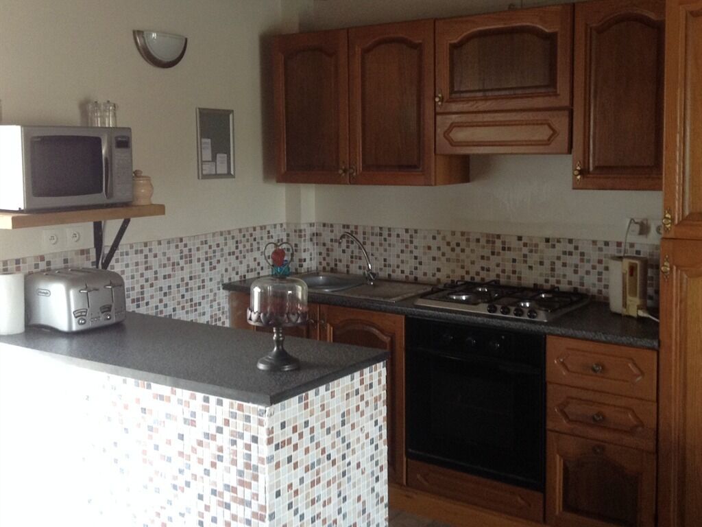 A kitchen with wooden cabinets, a microwave, a toaster, a sink, and a stove.