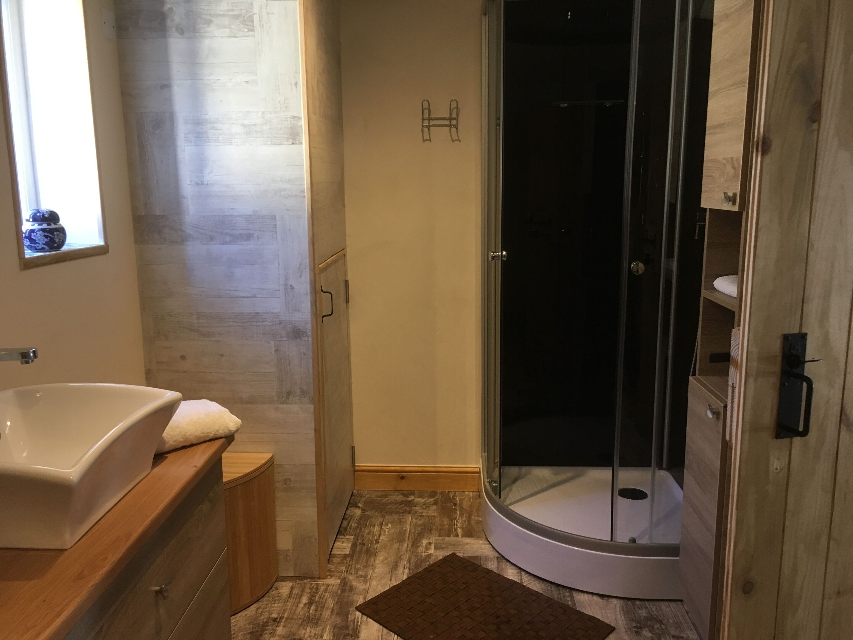 Een moderne badkamer met een vrijstaand bad, een douche met glazen wanden en een houten wastafelmeubel.