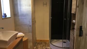 Een moderne badkamer met een vrijstaand bad, een douche met glazen wanden en een houten wastafelmeubel.