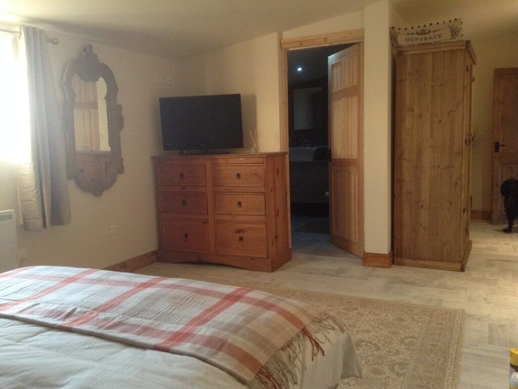 Ein Schlafzimmer mit Bett, Schminktisch, Fernseher und Kleiderschrank.