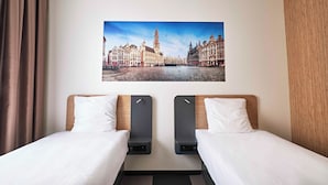 Ein Hotelzimmer mit zwei Betten, einem großen Fenster und Blick auf die Stadt.