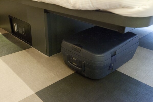 Una cama con un colchón, una mesita de noche y una maleta en el suelo.