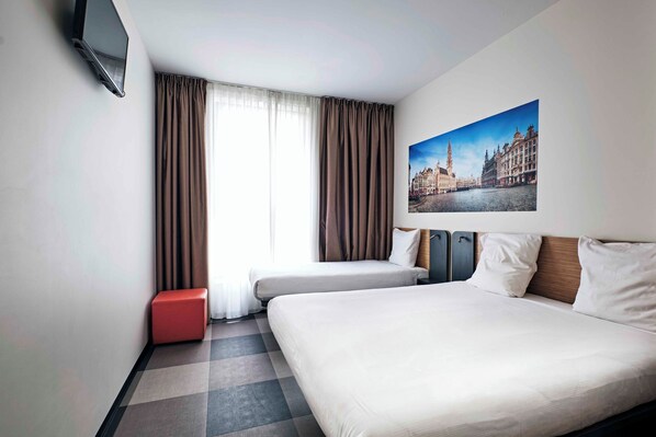 Una habitación de hotel con una cama, un televisor montado en la pared, una ventana con cortinas y un cuadro de un paisaje urbano.