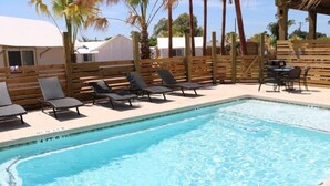 Una piscina con sillones de descanso y una terraza de madera.