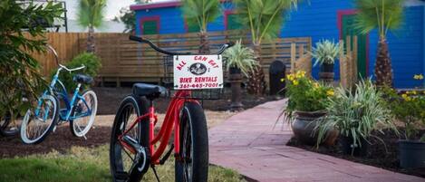 A red bicycle with a sign advertising bike rentals and a contact number.