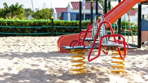 Ein Spielplatz mit Rutsche und Schaukeln auf Sandboden.