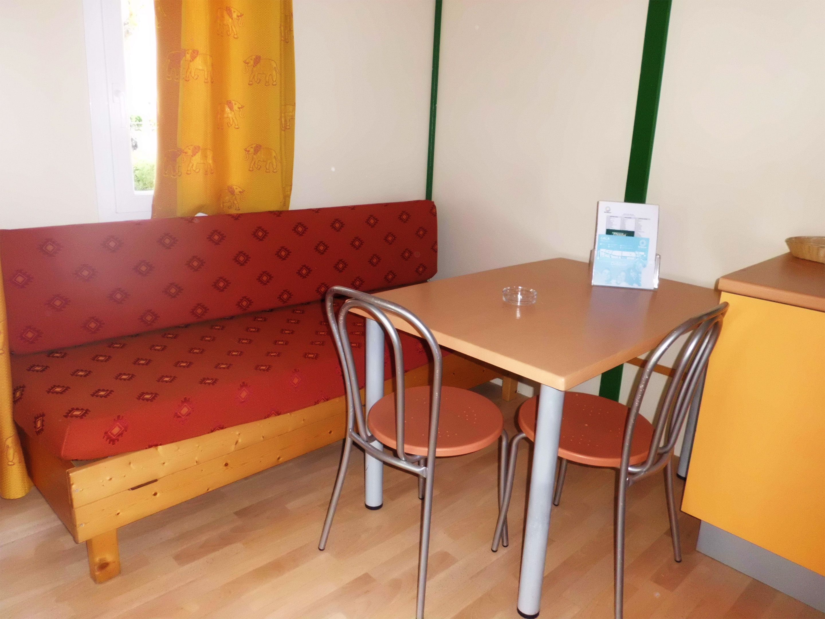 A small room with a wooden bench, a table, and four chairs.