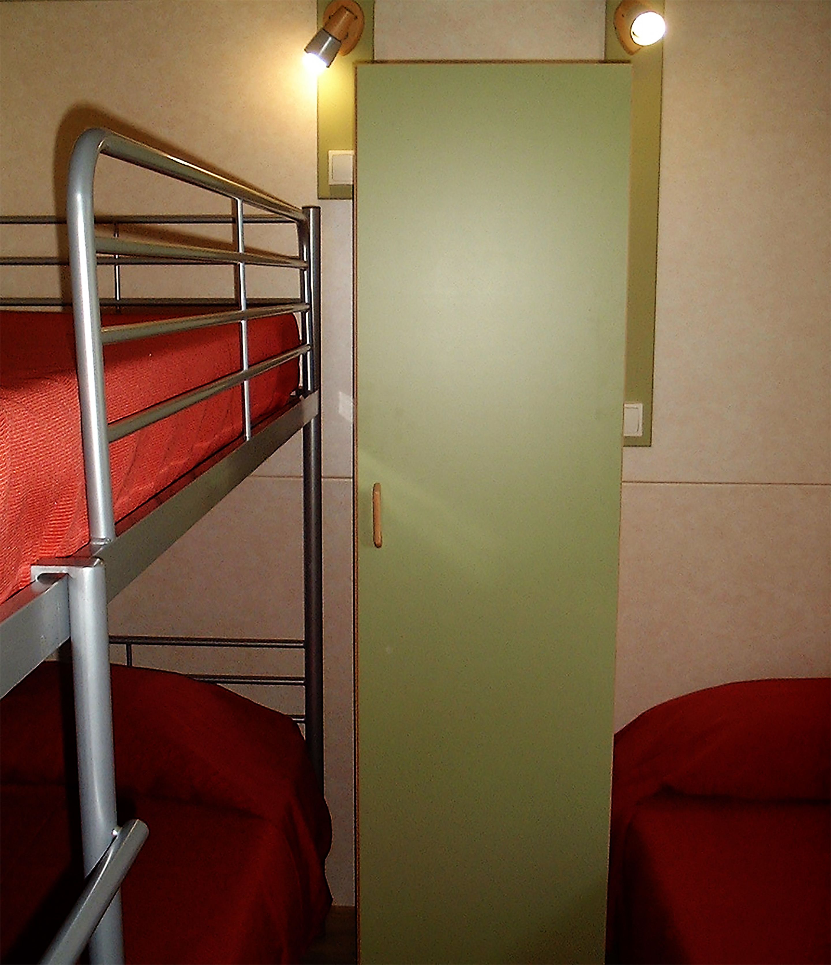 Ein Etagenbett mit einer grünen Tür und einem kleinen Fenster.