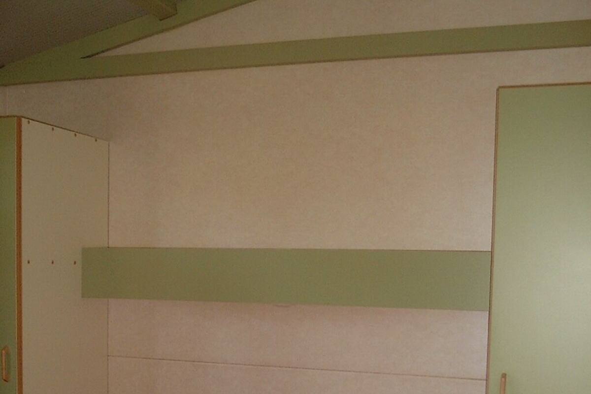 A room with a bunk bed, a green headboard, and a single door.