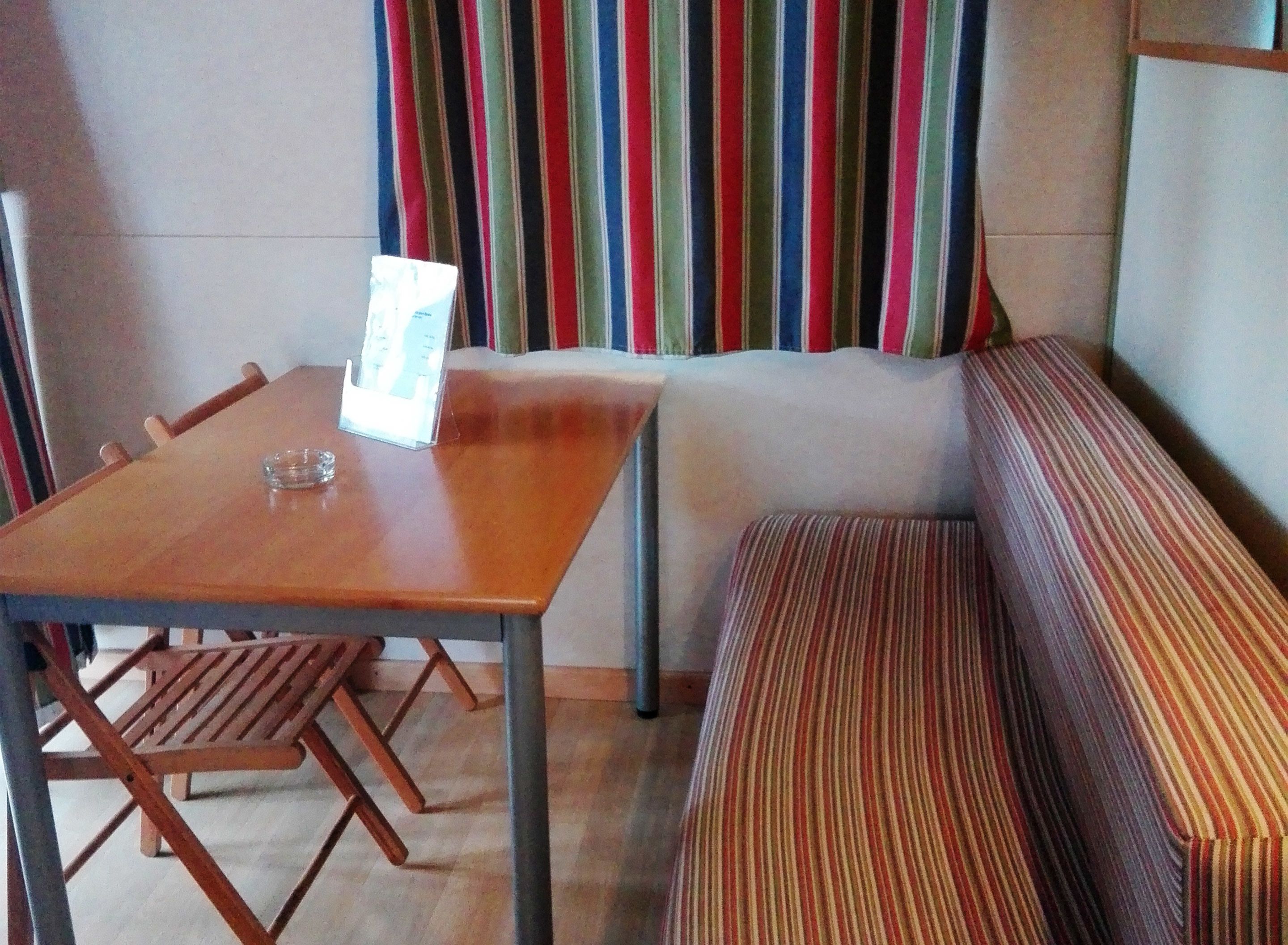 A room with a wooden table, a bench, and a striped curtain.