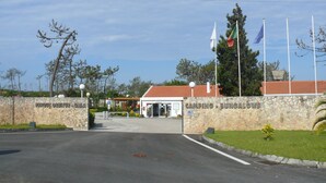 Ein Steineingang zu einem Campingplatz und Bungalowanlage mit Flaggen und blauem Himmel.