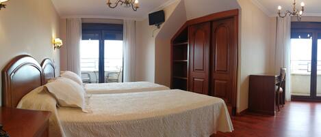 Habitación de hotel con dos camas, un armario de madera, un escritorio y una silla.