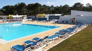 Una piscina con sillas reclinables azules y una zona cubierta.