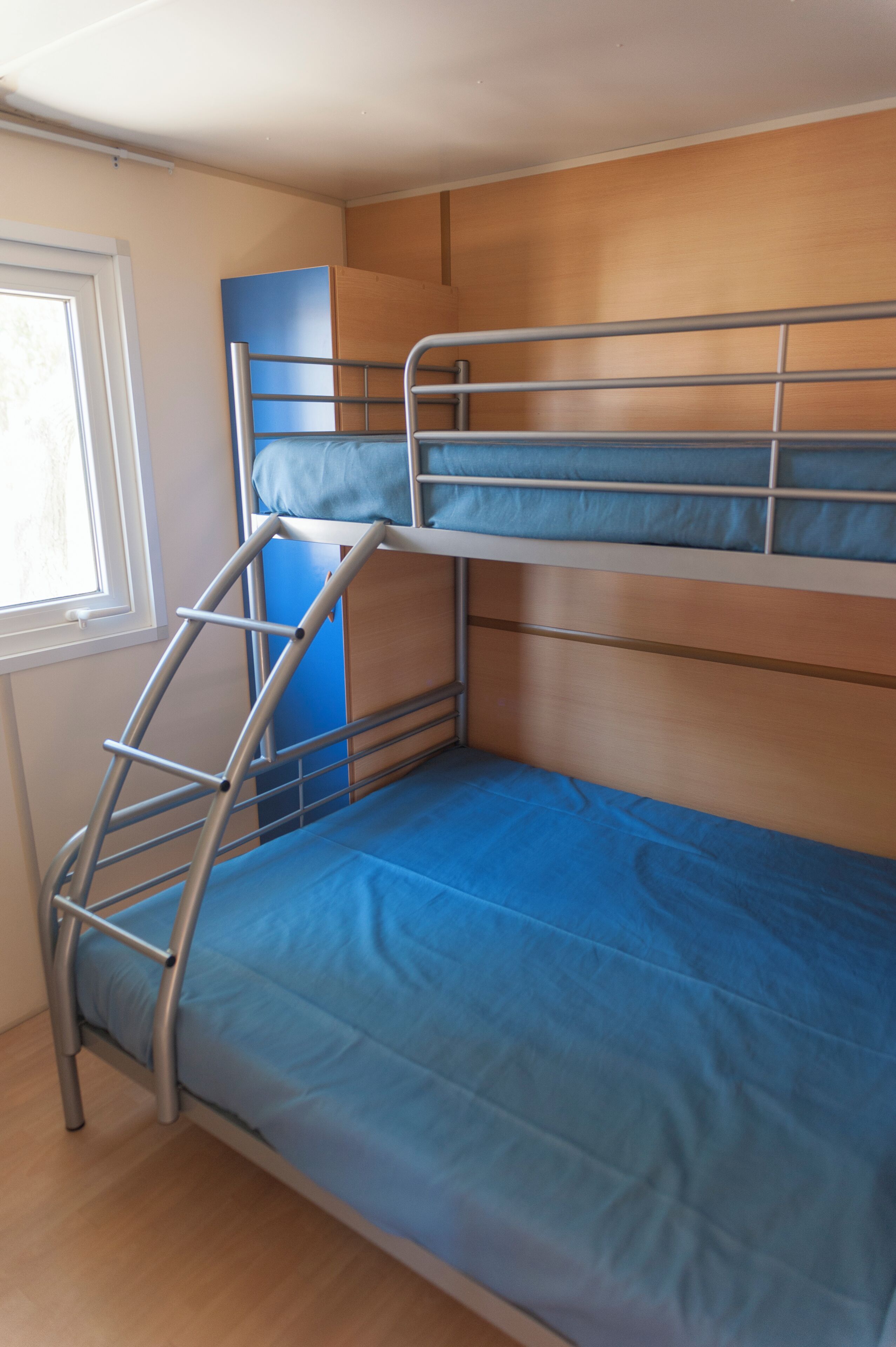 Ein Stockbett mit einer Leiter, einem Fenster und einer Holzwand.