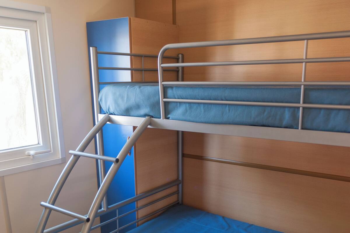 Ein Stockbett mit einer Leiter, einem Fenster und einer Holzwand.