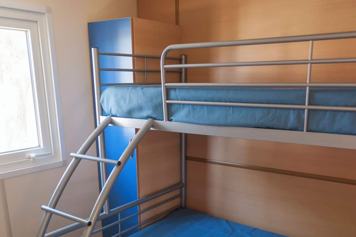 Un lit superposé avec une échelle, une fenêtre et un mur en bois.
