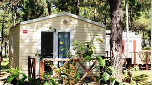 Una pequeña casa móvil de un solo nivel con fachada blanca, una puerta y un porche pequeño.