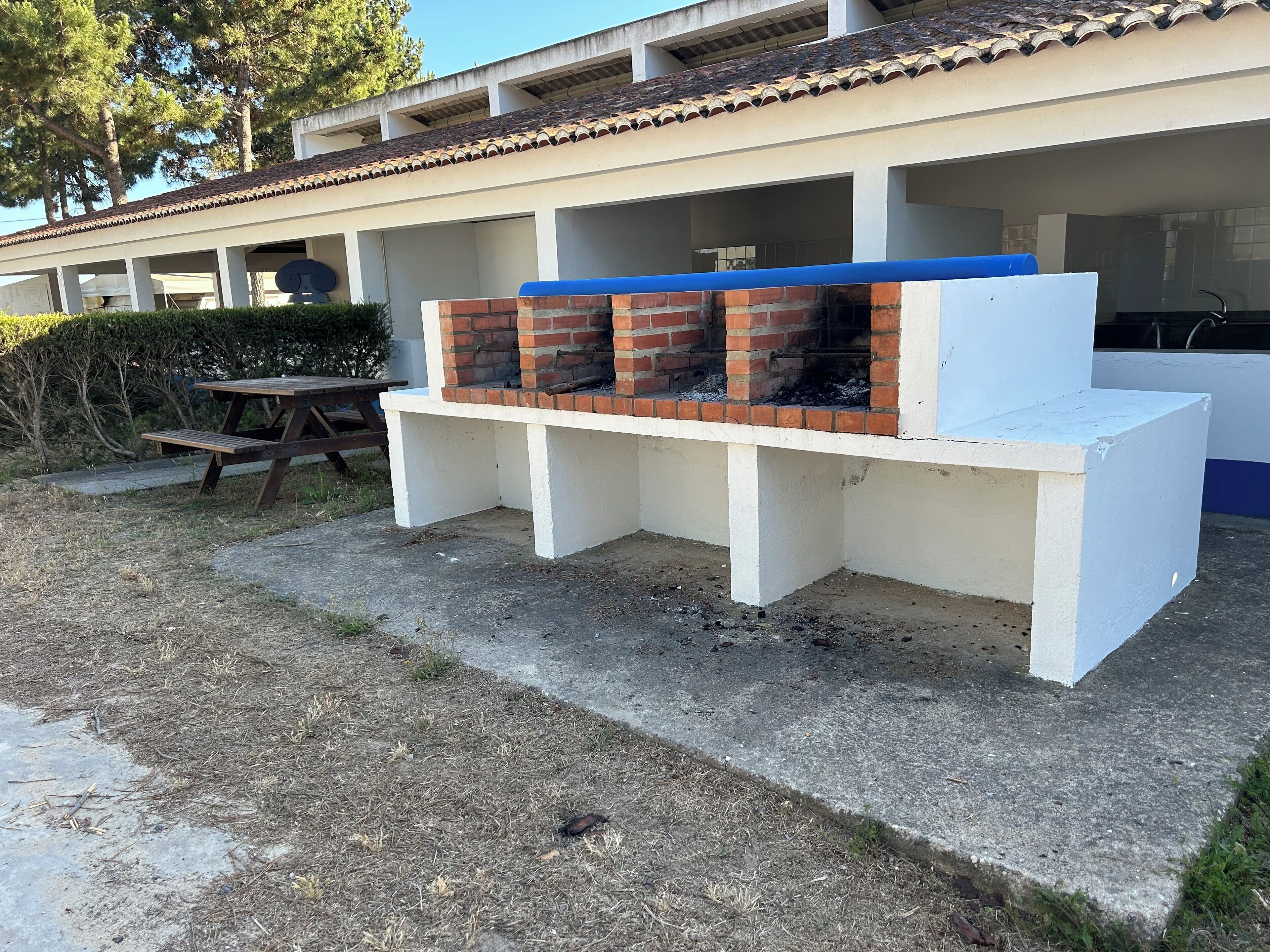 A barbecue area with a brick grill and a white bench.