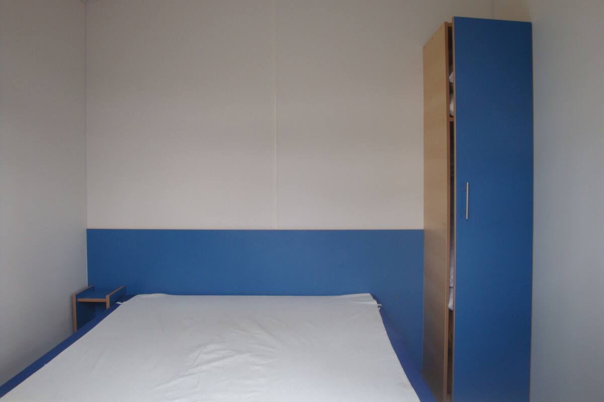 Ein Zimmer mit einem Bett, einem Schrank und einem kleinen Tisch.