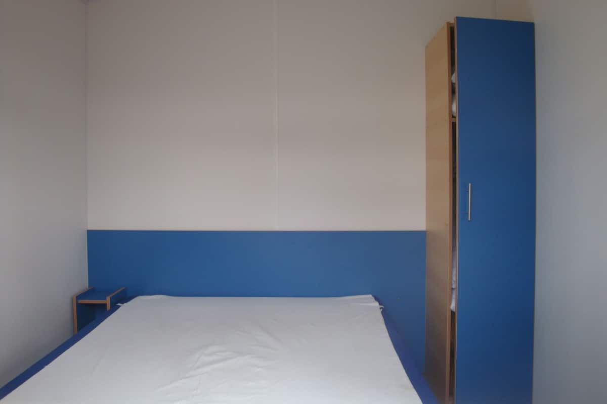 Une chambre avec un lit, une armoire et une petite table.