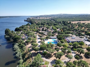 Vista aérea de una zona costera con piscina, rodeada de abundante vegetación y edificios residenciales.