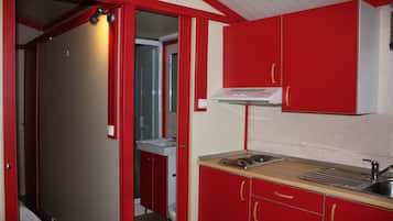 A compact kitchen with red cabinets, a sink, and a stove.
