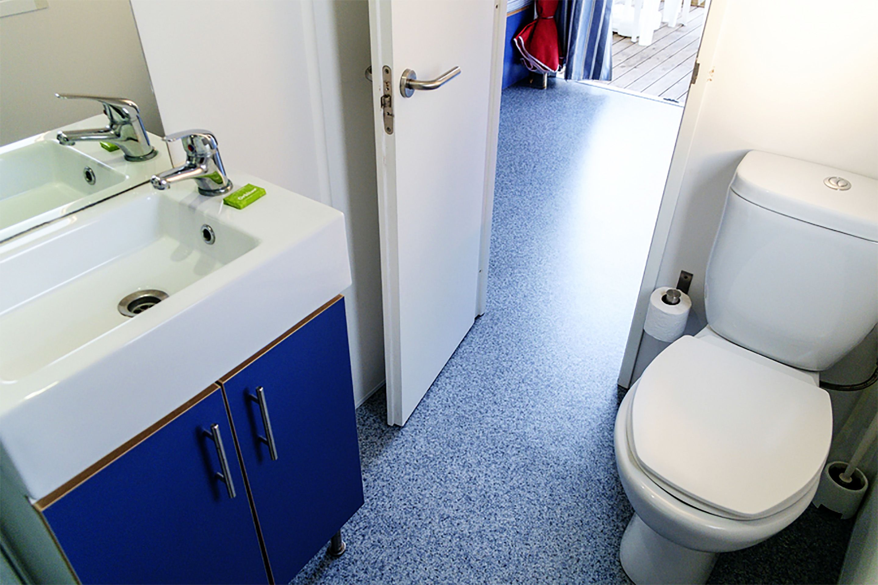 A bathroom with a white sink, blue cabinets, and a white toilet.
