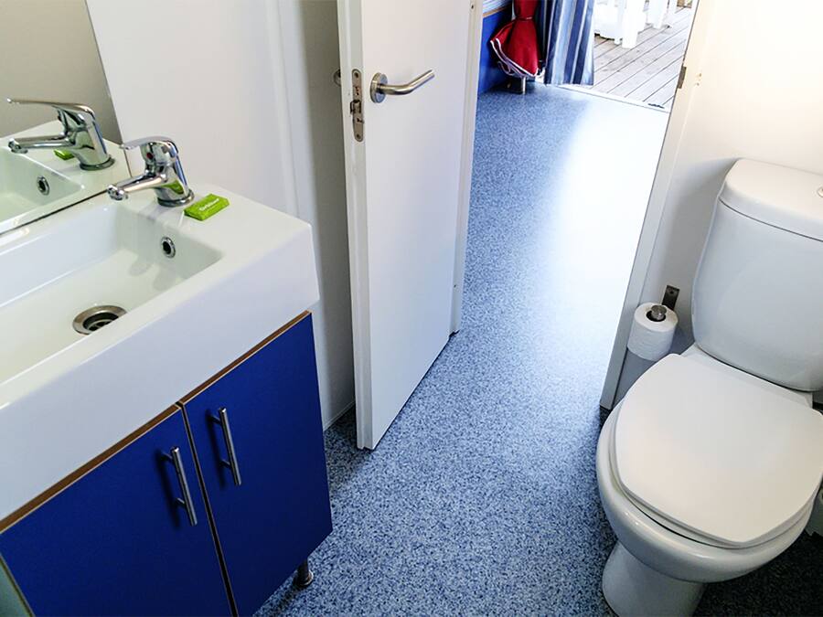 A bathroom with a white sink, blue cabinets, and a white toilet.