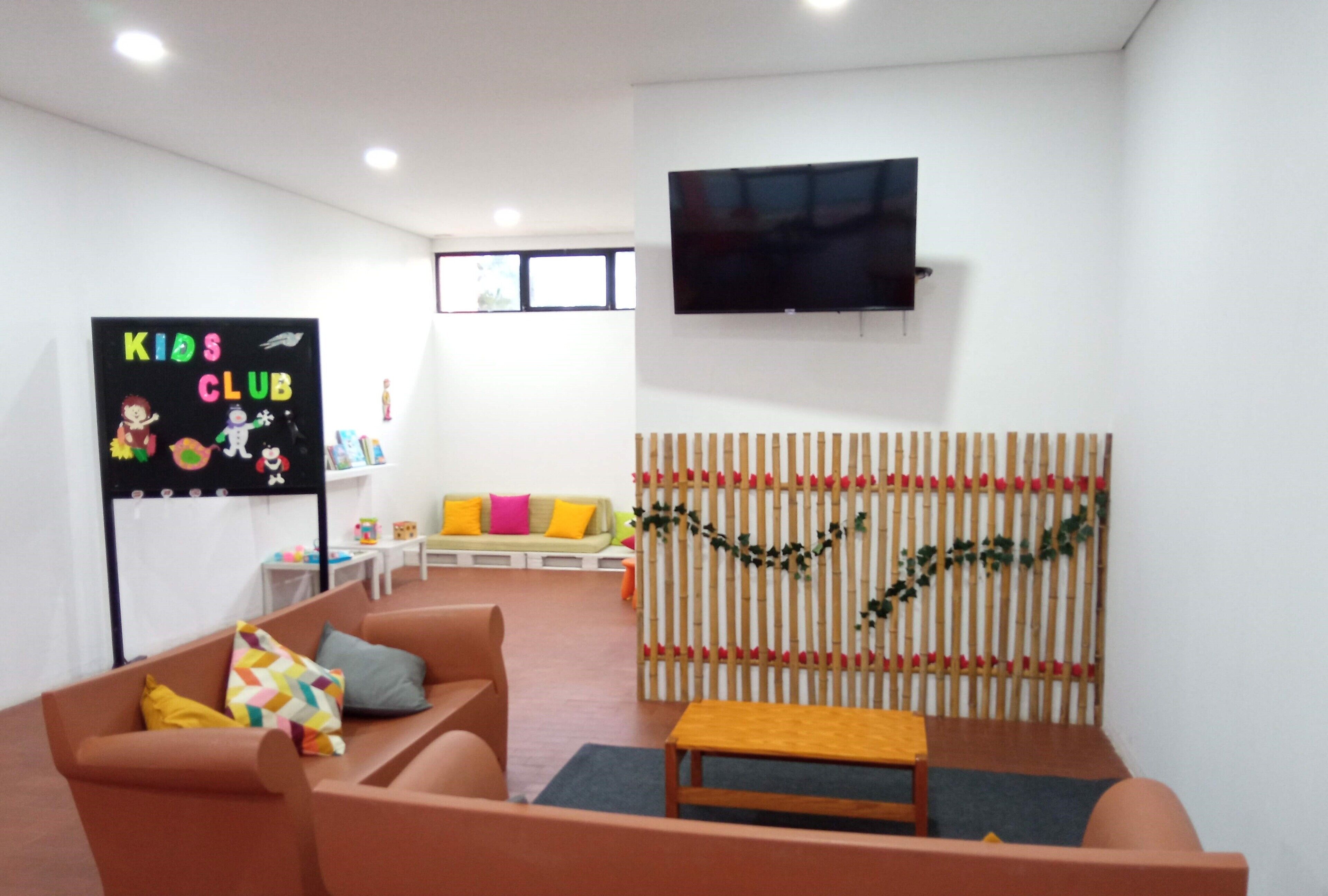 A children's play area with a TV, a sofa, and a wall with a heart decoration.