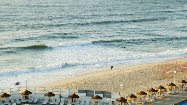 A beach with lounge chairs and umbrellas, a sandy shore, and the ocean. - Parque de Campismo Orbitur Sao Pedro De Moel (Marinha Grande)