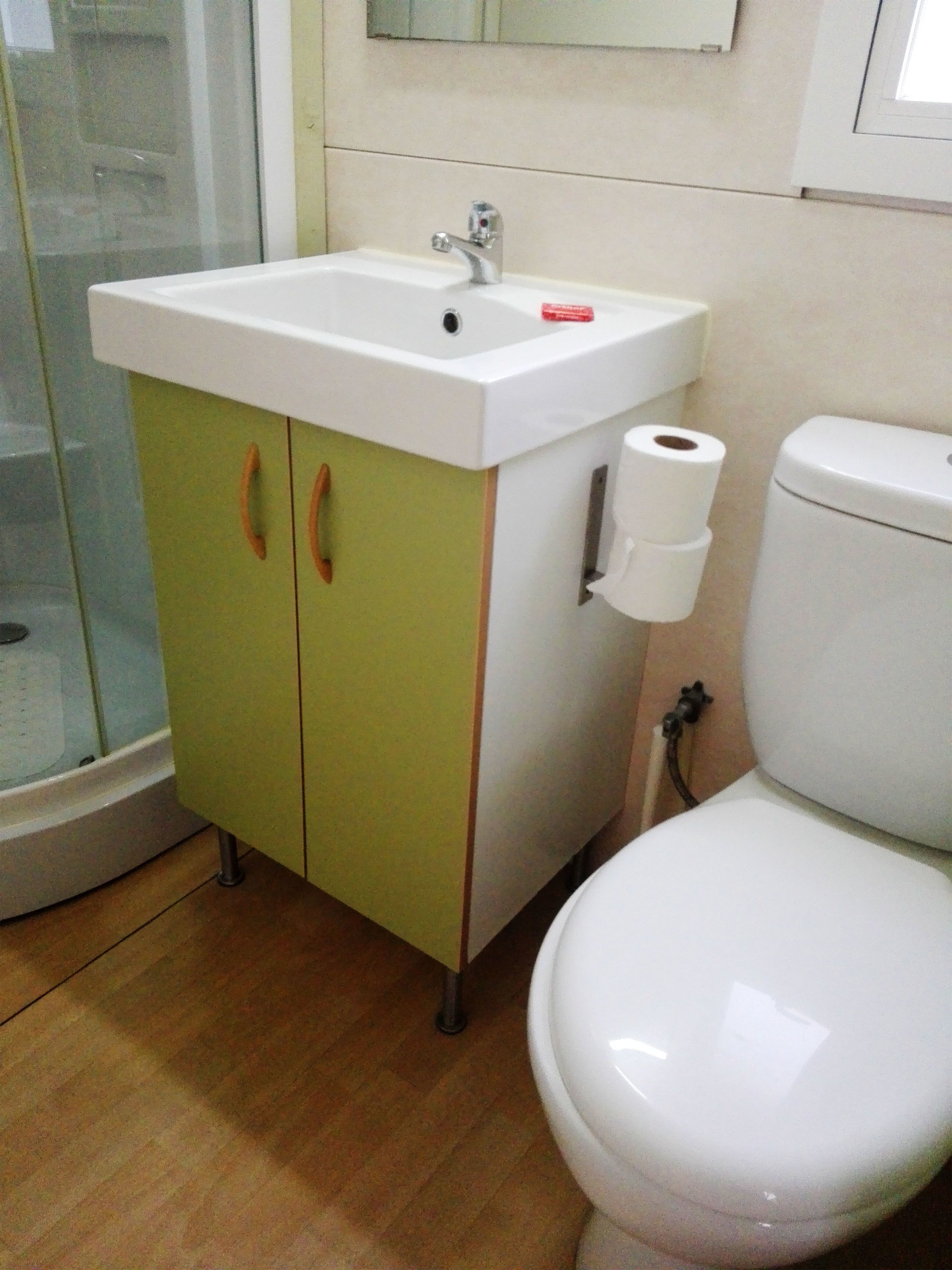 A bathroom with a white sink, green cabinet, and a white toilet.