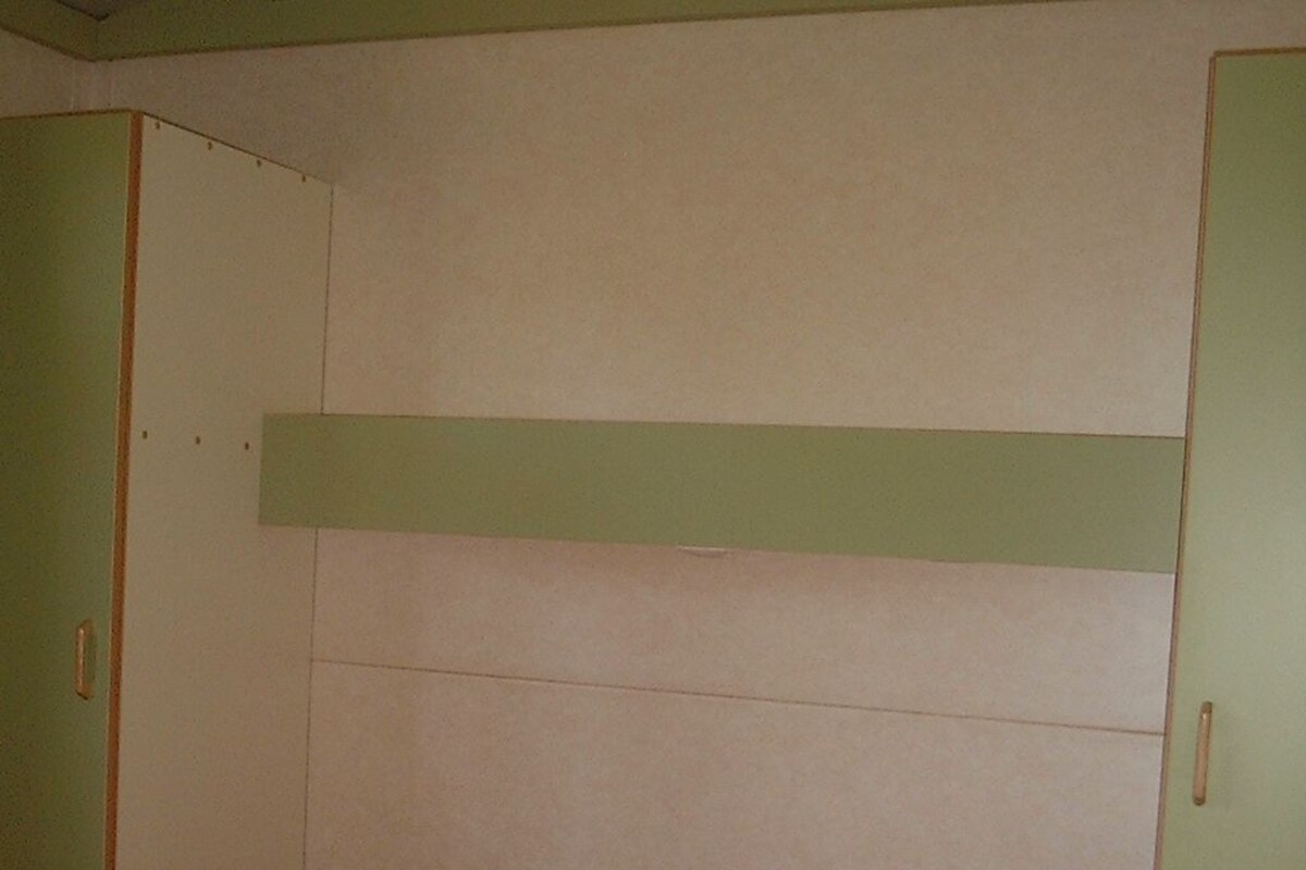 A room with a bed, green walls, and a white ceiling.
