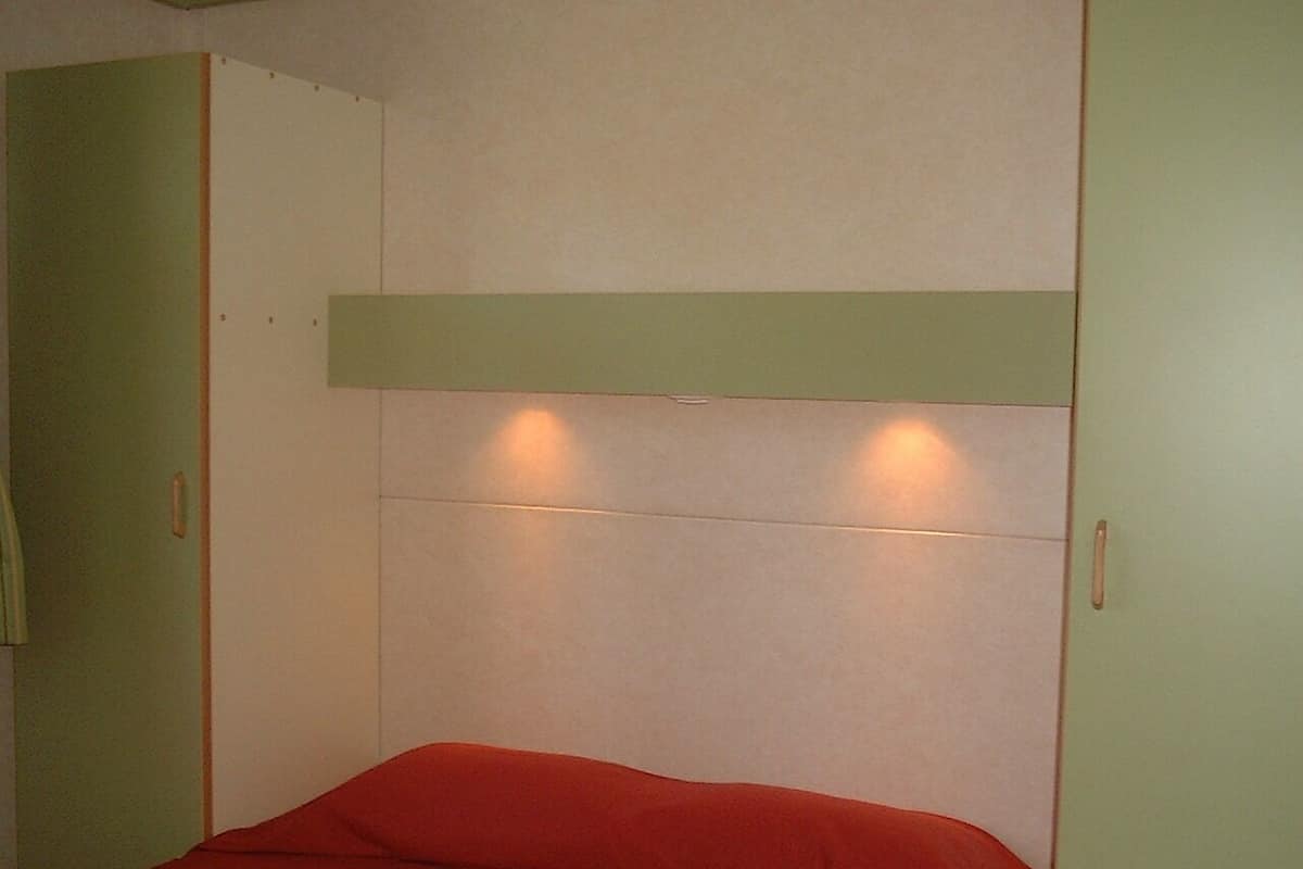 A room with a bed, green walls, and a white ceiling.