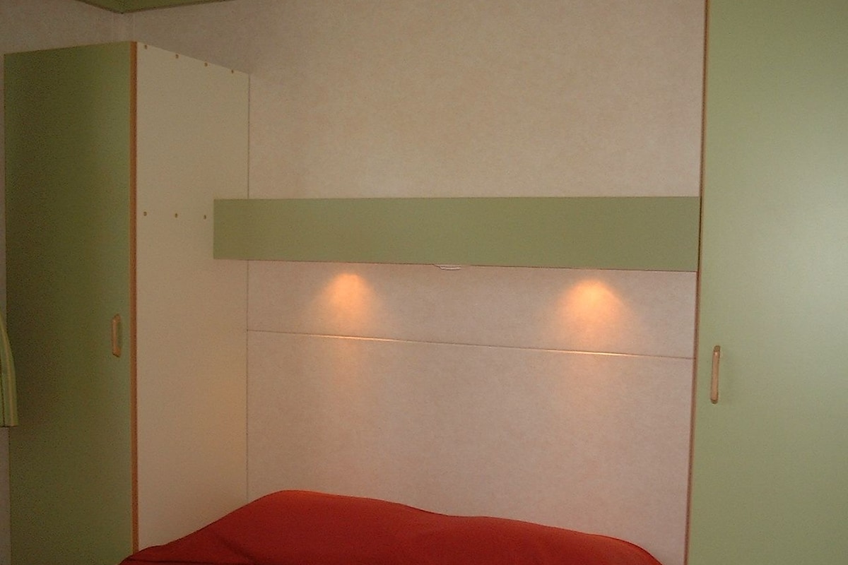 Una habitación con una cama, paredes verdes y techo blanco.