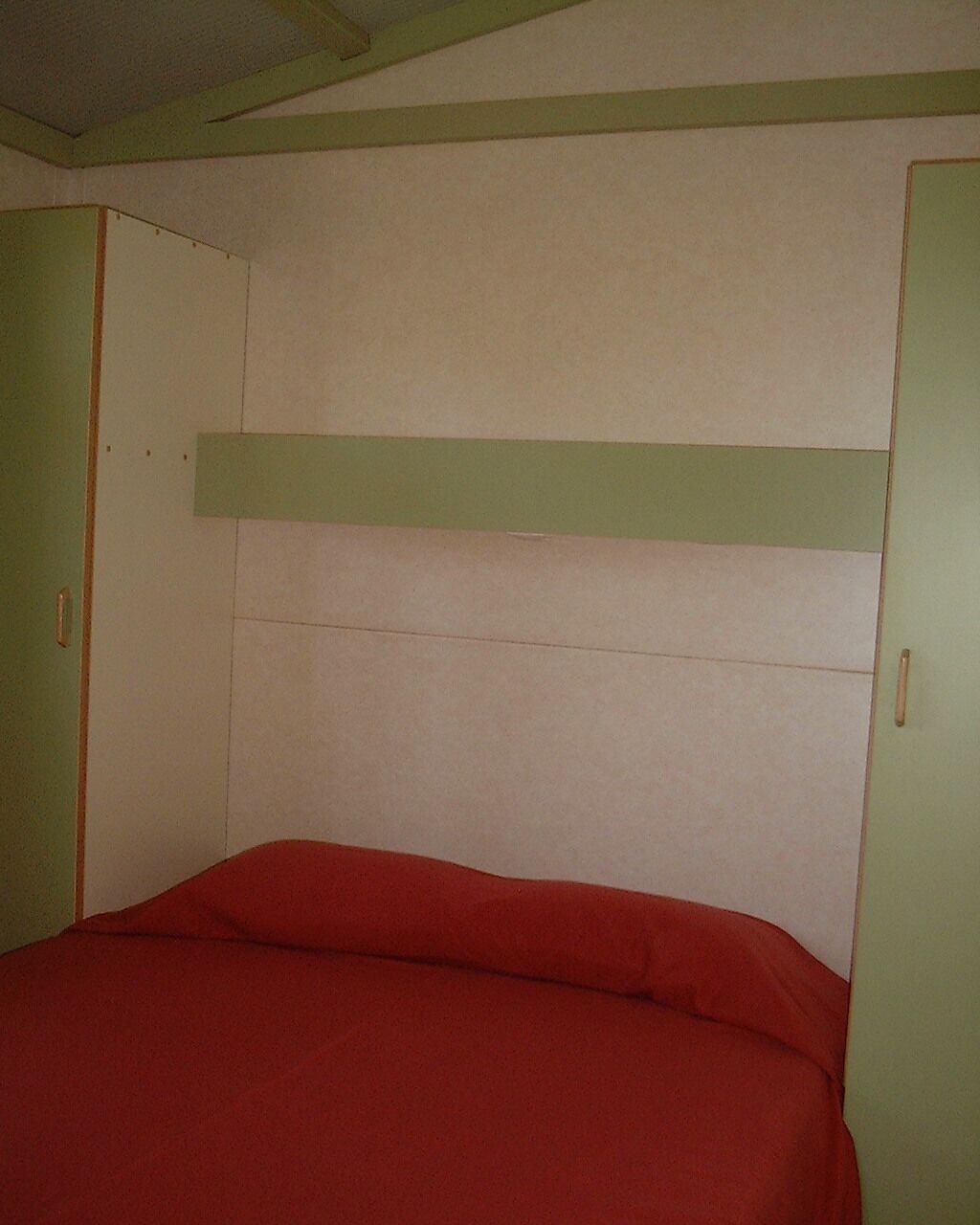 Una habitación con cama, paredes verdes y techo blanco.