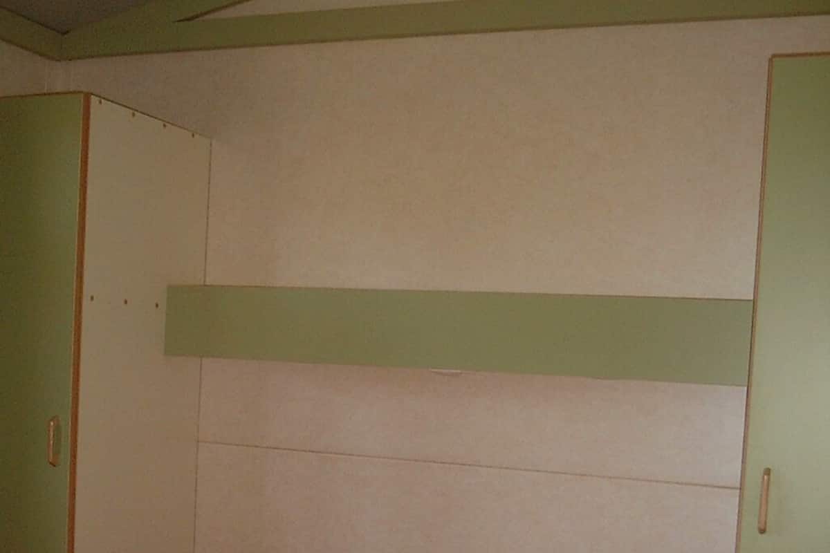 A room with a bed, green walls, and a white ceiling.